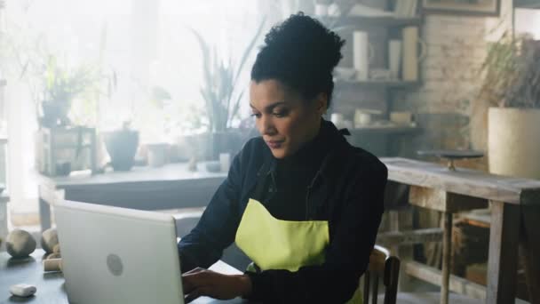 Mujer Potter está trabajando en el ordenador portátil en el lugar de trabajo — Vídeos de Stock