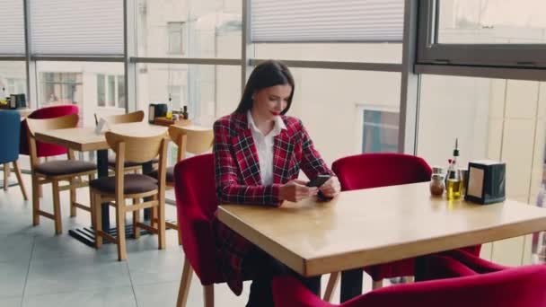 Frau in roter Jacke entspannt sich im Café — Stockvideo