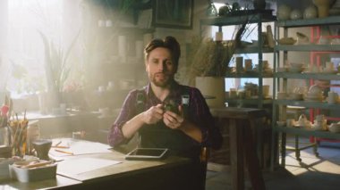 Adam kahve içiyor ve kameraya bakıyor.