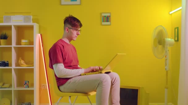Człowiek pracuje na laptopie przed wentylatorem elektrycznym — Wideo stockowe