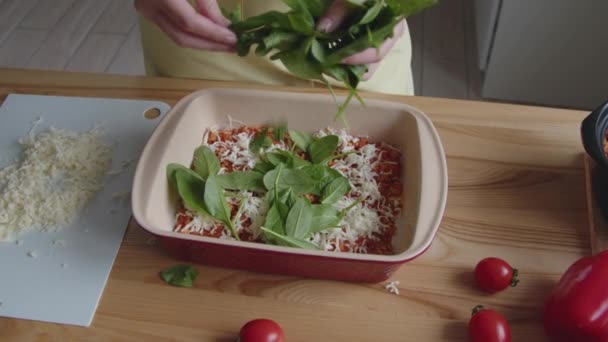 Donna si sta diffondendo foglie di spinaci freschi in forno — Video Stock