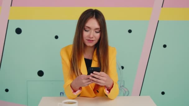Mladá bruneta dáma ve žluté bundě používá gadget — Stock video