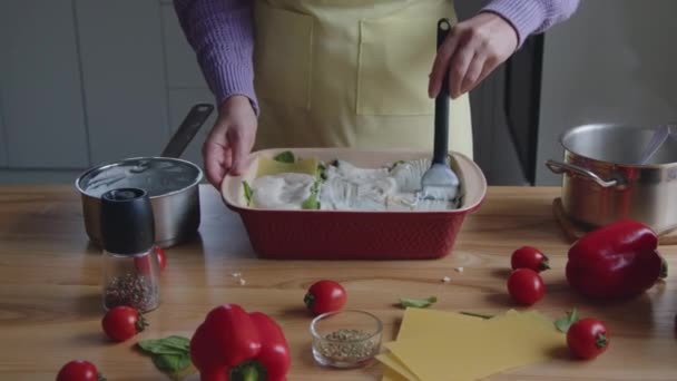 Mujer está esparciendo salsa en fideos de lasaña — Vídeos de Stock