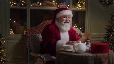 Noel Baba evinin arka bahçesinde oturuyor, Kuzey Kutbu 'nda, ve çocuklardan gelen mektupları okuyor lütfen, sihir sezonuna hazırlanıyor, Ağır çekim.