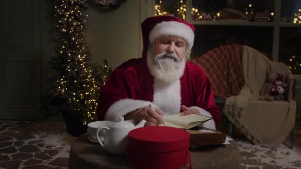 Papai Noel Está Trabalhando Sua Residência Fazendo Algumas Notas Planejador — Vídeo de Stock