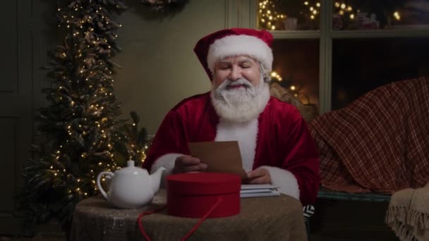 Санта Клаус Працює Своєму Подвір Прикрашений Світлом Читанням Листа Посміхається — стокове відео