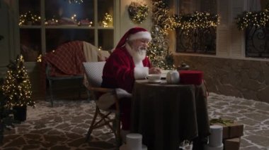 Noel Baba arka bahçesinde zevkle çalışıyor, hediyelerin bir listesini yapıyor, çocukların ve yetişkinlerin tüm isteklerini yazıyor, Noel ruhu, ağır çekim.