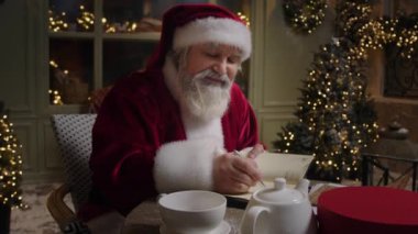 Meşgul Noel Baba evinde çalışıyor, Noel tatili için planlar yapıyor, planlamacı, ön plan, ağır çekim.
