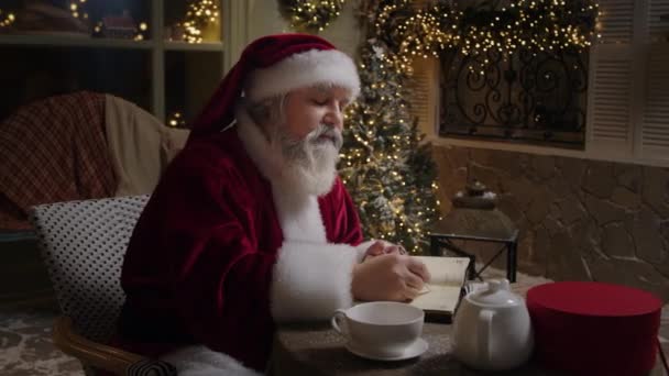 忙碌的圣诞老人正在他的家里工作 在计划员那里做一些笔记 处理信件 准备圣诞节 慢动作 — 图库视频影像