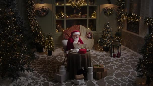 Απασχολημένος Άγιος Βασίλης Εργάζεται Στο Σπίτι Του Αργά Βράδυ Χρησιμοποιώντας — Αρχείο Βίντεο