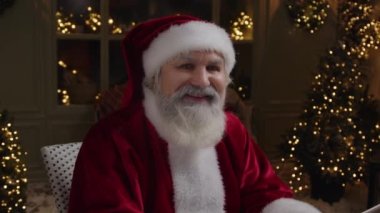Kırmızı kostümlü mutlu Noel Baba kameraya gülümsüyor, kış tatili havasını paylaşıyor, sihirli Noel zamanı, Kapatın, Ağır çekim.