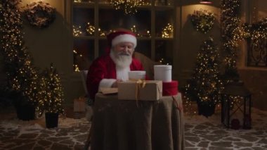 Noel Baba gece geç saatlere kadar çalışıyor. Tatil sezonuna hazırlanıyor. Noel hediyelerini imzalıyor..