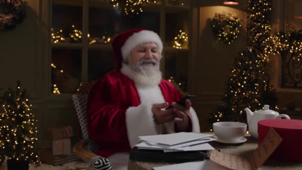 Święty Mikołaj Siedzi Podwórku Rozmawia Przez Telefon Komórkowy Robi Przygotowania — Wideo stockowe