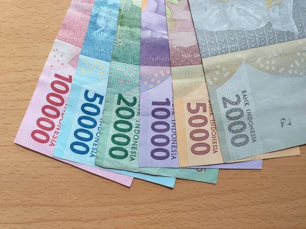 一堆印度尼西亚货币叫做 Rupiah 像扇子一样排列在木制桌子上 — 图库照片