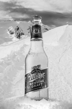 MOSCOW, RUSSIA - Mayıs 07, 2020: Güzel dağların arka planında kar bulunan soğutulmuş Miller Hakiki Bira Şişesi. Miller Birası, SABMiller 'ın sahibi olduğu Miller Bira Şirketi' nin bir ürünüdür..