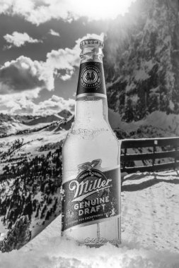 MOSCOW, RUSSIA - Mayıs 07, 2020: Güzel dağların arka planında kar bulunan soğutulmuş Miller Hakiki Bira Şişesi. Miller Birası, SABMiller 'ın sahibi olduğu Miller Bira Şirketi' nin bir ürünüdür..