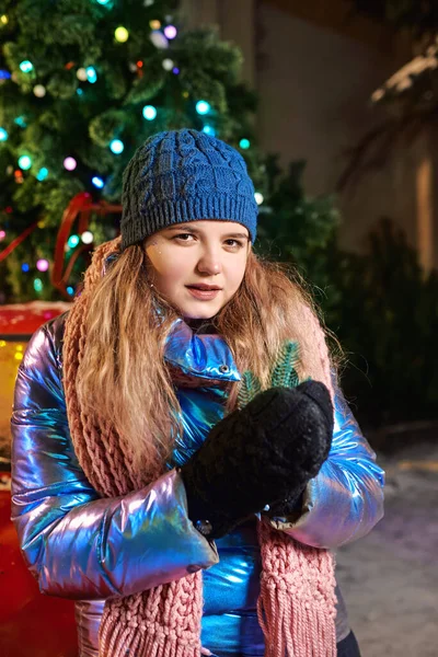 Atkısı, şapkası, ceketi, kırmızı vintage arabası ve açık havada noel ağacı olan ladin desenli eldivenleri olan mutlu beyaz bir kadın. Yeni yıl, eğlence, kış konsepti