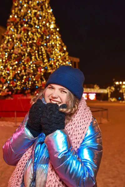 Eşarplı, şapkalı, ceketli, dışarıdaki noel ağacının yanında eldivenli mutlu, beyaz bir kadın. Yeni yıl, eğlence, kış konsepti 