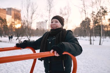 Şapkalı ve spor ceketli son sınıf öğrencisi. Kar parkında spor egzersizleri yapıyor. Kış, yaş, spor, aktivite, sezon konsepti