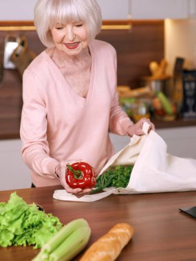 Son sınıf neşe saçan kadın, modern mutfakta bakkaliyeyi yeniden paketliyor. Yiyecek, beceri, yaşam tarzı konsepti