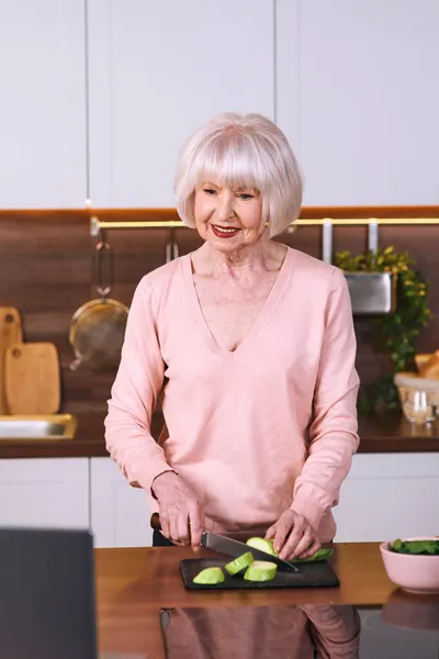 Mulher Alegre Sênior Está Cozinhando Cozinha Moderna Por Laptop Alimentação — Fotografia de Stock