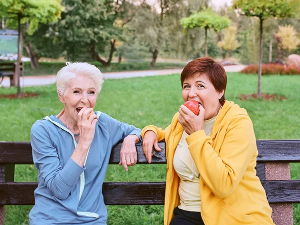 Dos Mujeres Maduras Comiendo Manzanas Banco Después Hacer Ejercicios Deportivos —  Fotos de Stock