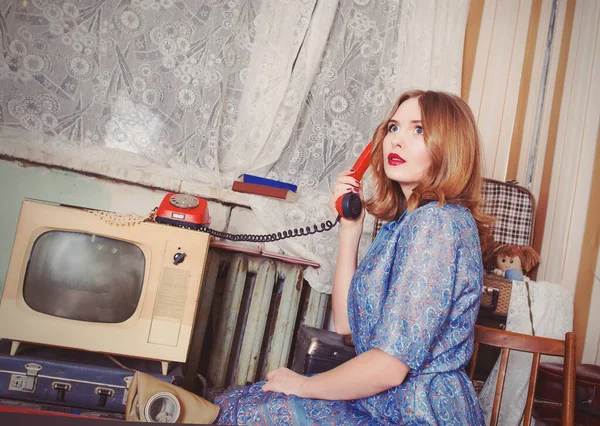 portrait of Old fashioned woman in USSR style talking on the old telephone in retro interior