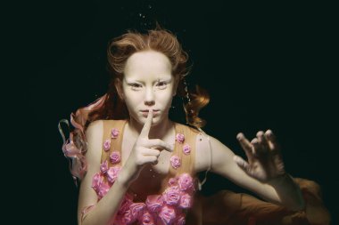 Gül su altında yapılan elbiseli genç Kızıl saçlı kız