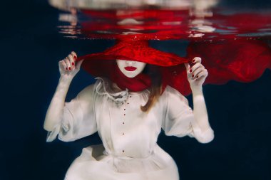 Woman in red hat and red scarf underwater