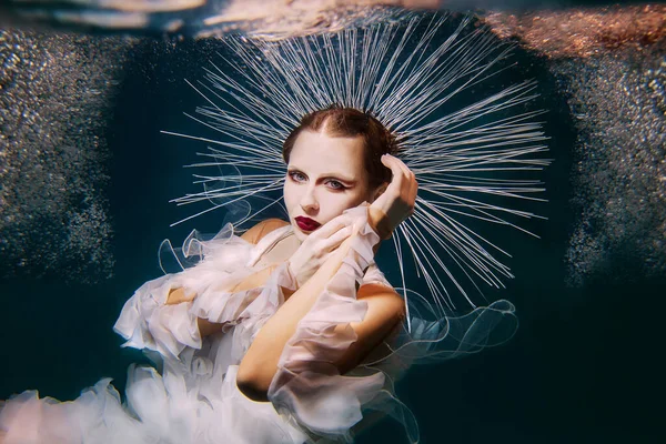 Beautiful woman with red lips and in women's jewellery underwater as the Virgin Mary