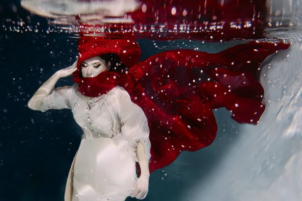 Woman in red hat and red scarf underwater