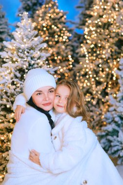 Asyalı anne ve Kafkasyalı kızı dışarıda noel ağacının yanında. Aşk, aile, çeşitlilik, tatil kavramı