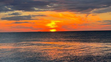 Kapalı deniz kumsalı. Renkli altın rengi günbatımı gökyüzü sakinlik, dinlendirici güneş ışığı yaz titreşimleri, sakin deniz. Sahilde gün batımı. Meditasyon okyanusu ve gökyüzü arka planı. Suyun üzerinde ufuk.. 
