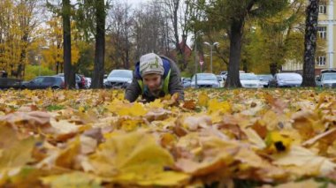 Çocuk şehir ortamında sonbahar sarısı yapraklarıyla oynuyordu.