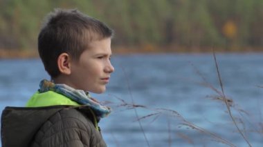 Çocuk gölün kıyısında tek başına duruyor.