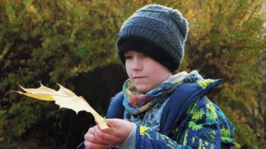 Oğlan sonbahar boyunca parkta büyük bir merdivende oturur.