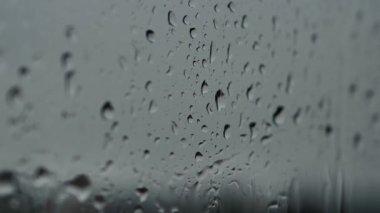 Pencerenin arkasında şiddetli yağmur yağıyor. Pencereye düşer, aşağı kayar.