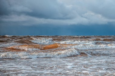 Deniz dalgalarında gün ışığı parlar. Rüzgar dalgaları kıyıya vurur. Kışın, toprak seti taşlarla kaplıdır.