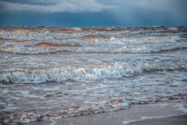 Deniz dalgalarında gün ışığı parlar. Rüzgar dalgaları kıyıya vurur. Kışın, toprak seti taşlarla kaplıdır.