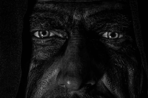 Kızgın bakışlı ve boyalı yüzlü bir Viking parlak gözlerle karanlığa bakar.