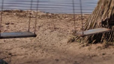 Oyun alanı kapalı, yakın çekim, salıncak hareketleri. Göl kenarındaki salıncak rüzgarda hareket ediyor.