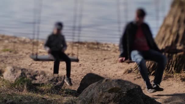 Children Rocked Swing Lake Faces Blurred Selective Focus — стоковое видео