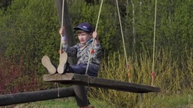 Büyük bir salıncakta sallanan bir çocuk. Çocuk ahşap salıncakta oturuyor.