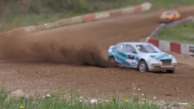 Çakıl taşı pistinde araba yarışı, yarışmaya katılarak birincilik için mücadele. Taşlar arabanın lastiklerinden uçuyor. Arabalar katılıyor. Brenguli.