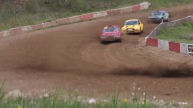 Çakıl taşı pistinde araba yarışı, yarışmaya katılarak birincilik için mücadele. Taşlar arabanın lastiklerinden uçuyor. Arabalar katılıyor. Brenguli.