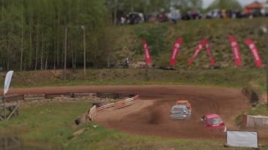 Çakıl taşı pistinde araba yarışı, yarışmaya katılarak birincilik için mücadele. Taşlar arabanın lastiklerinden uçuyor. Arabalar katılıyor. Brenguli.