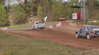 Çakıl taşı pistinde araba yarışı, yarışmaya katılarak birincilik için mücadele. Taşlar arabanın lastiklerinden uçuyor. Arabalar katılıyor. Brenguli.