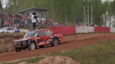 Çakıl taşı pistinde araba yarışı, yarışmaya katılarak birincilik için mücadele. Taşlar arabanın lastiklerinden uçuyor. Arabalar katılıyor. Brenguli.