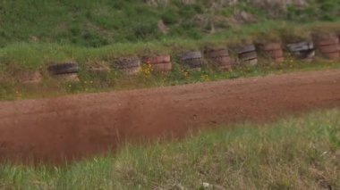 Çakıl taşı pistinde araba yarışı, yarışmaya katılarak birincilik için mücadele. Taşlar arabanın lastiklerinden uçuyor. Arabalar katılıyor. Brenguli.