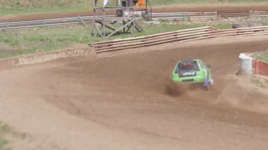Çakıl taşı pistinde araba yarışı, yarışmaya katılarak birincilik için mücadele. Taşlar arabanın lastiklerinden uçuyor. Arabalar katılıyor. Brenguli.